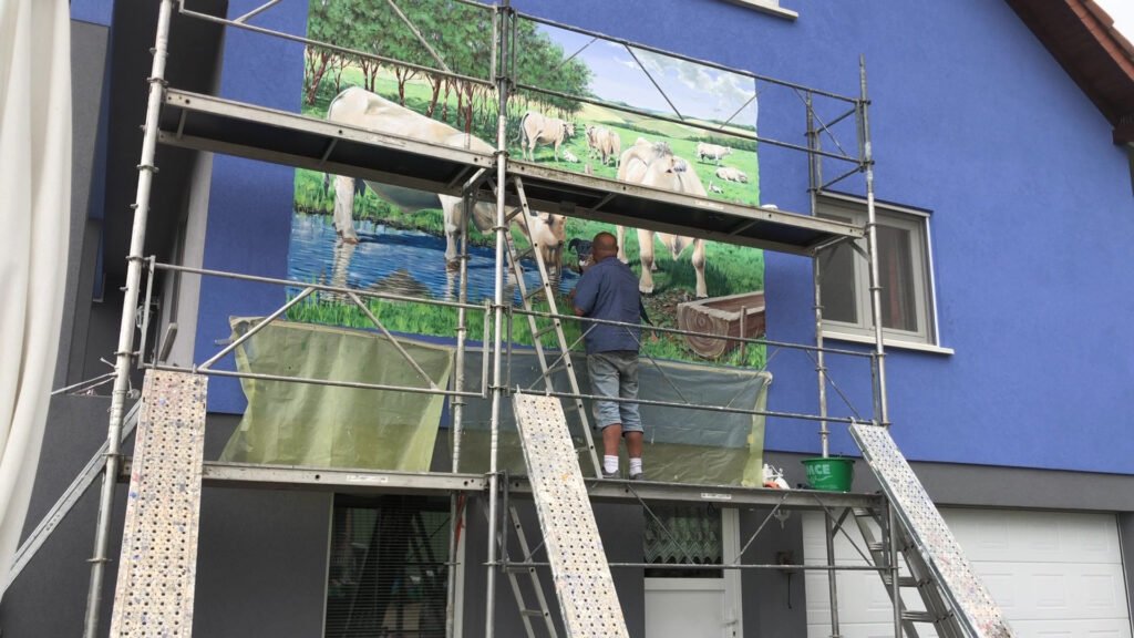Philippe DEGOTT peint sur le mur d’une maison